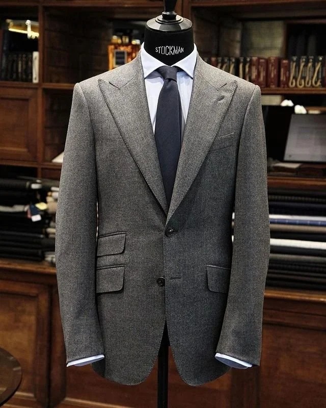 Costume gris en flanelle avec cravate sombre, présenté sur buste dans la boutique