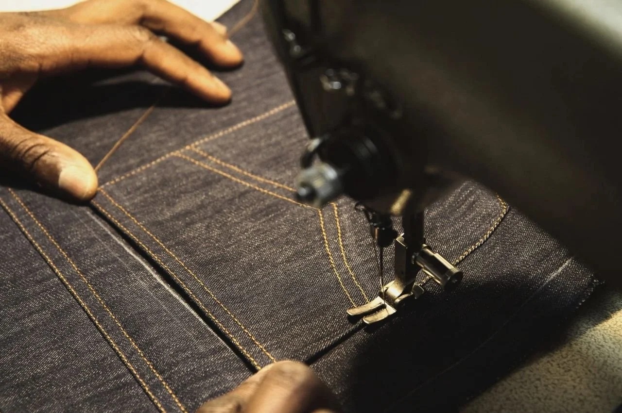 Mains guidant un tissu sous le pied d’une machine à coudre ancienne