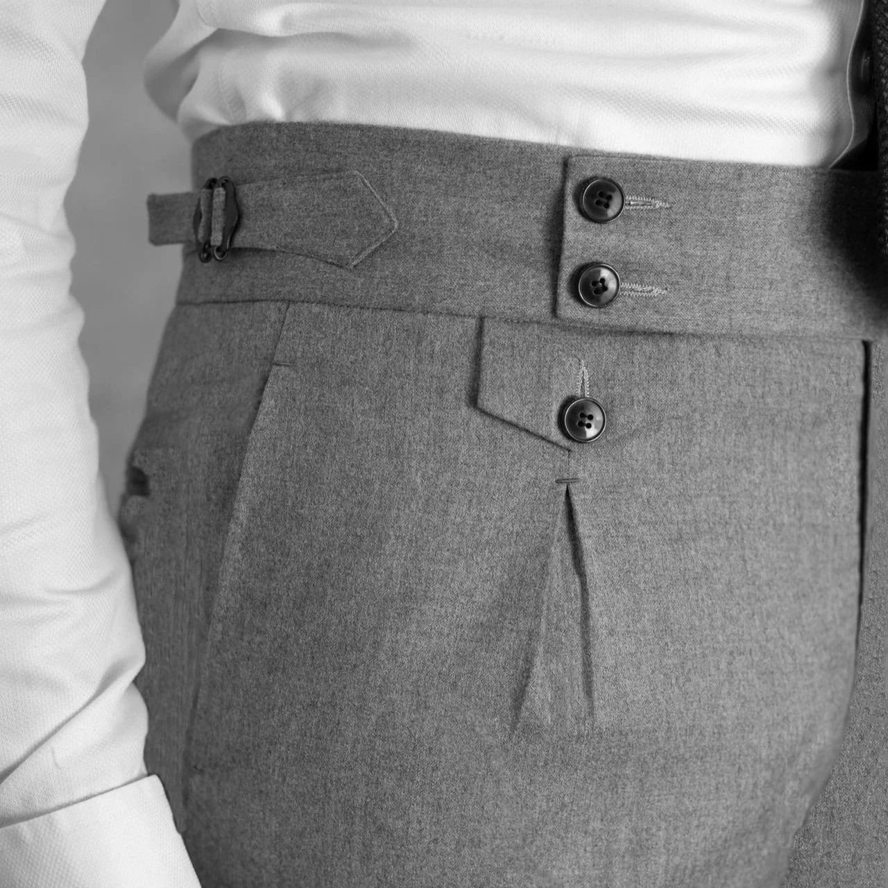 Détail de la taille d’un pantalon en flanelle grise à ajusteurs latéraux et boutons de corne